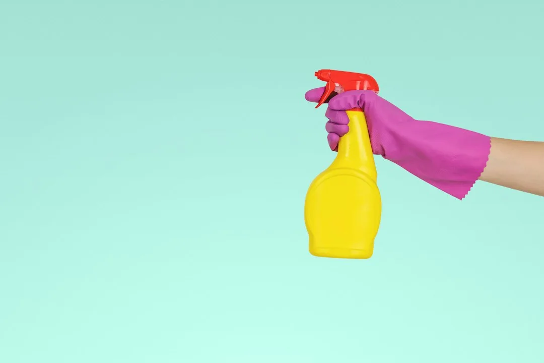 Amber glass spray bottle with white nozzle containing homemade vinegar household cleaner