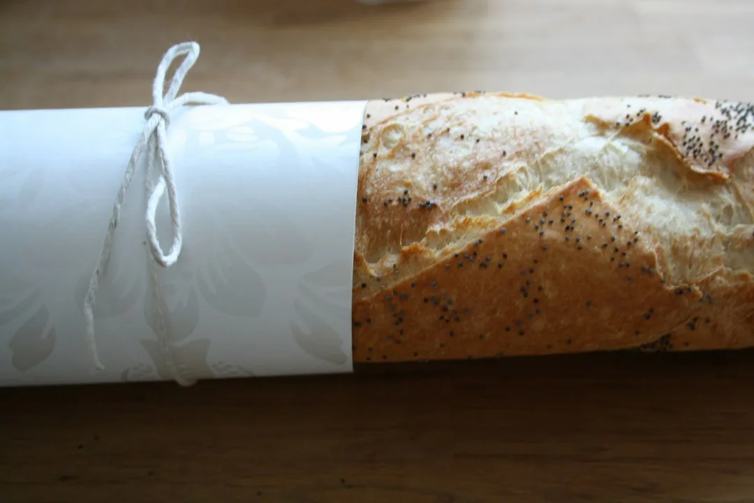 Patterned reusable beeswax food wrap sealing loaf of homemade sourdough bread on counter
