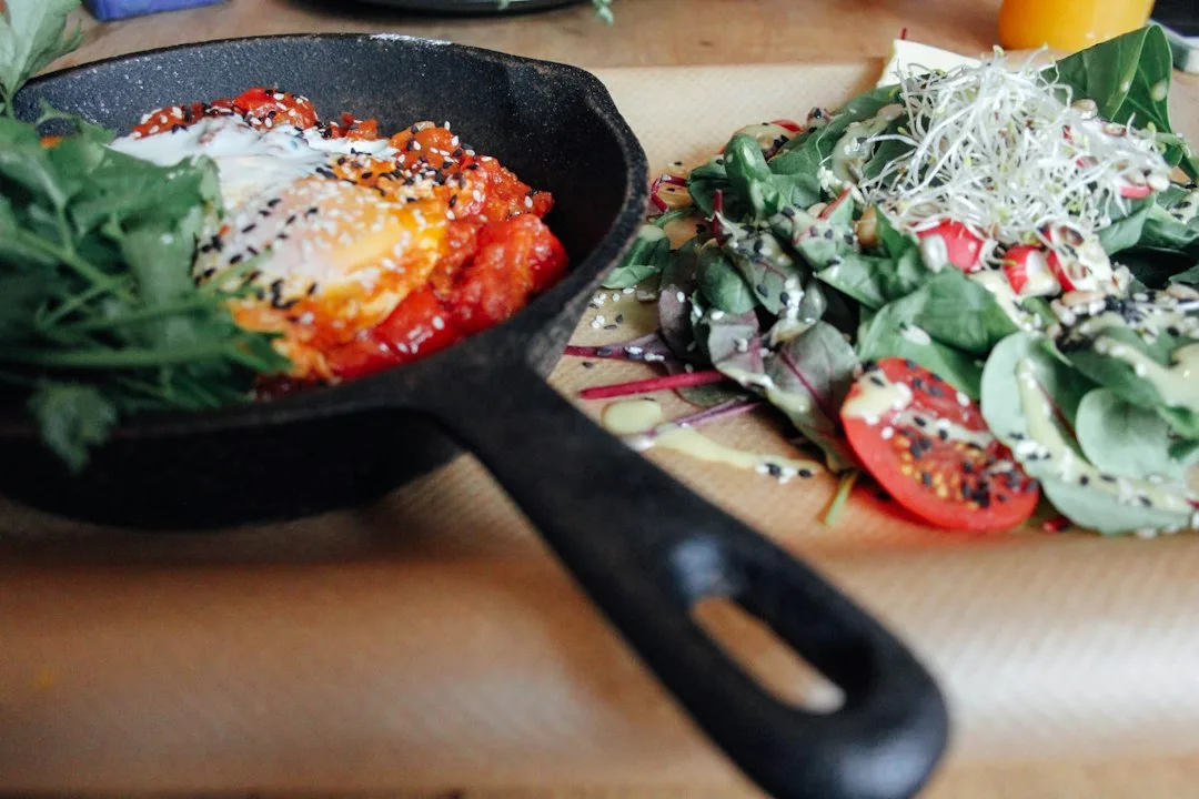 Sizzling cast iron skillet filled with colorful roasted vegetables and chicken on stove