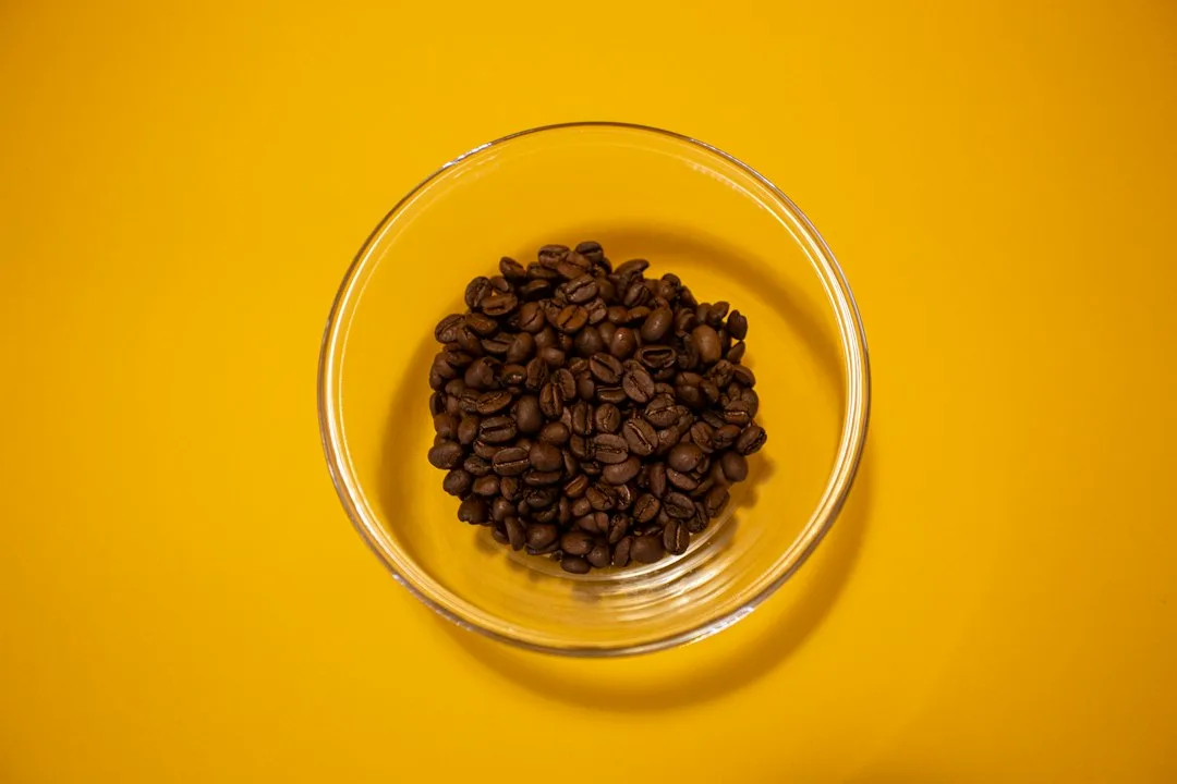 Warm cooked brown rice mixed with seasoned black beans in clear glass kitchen bowl