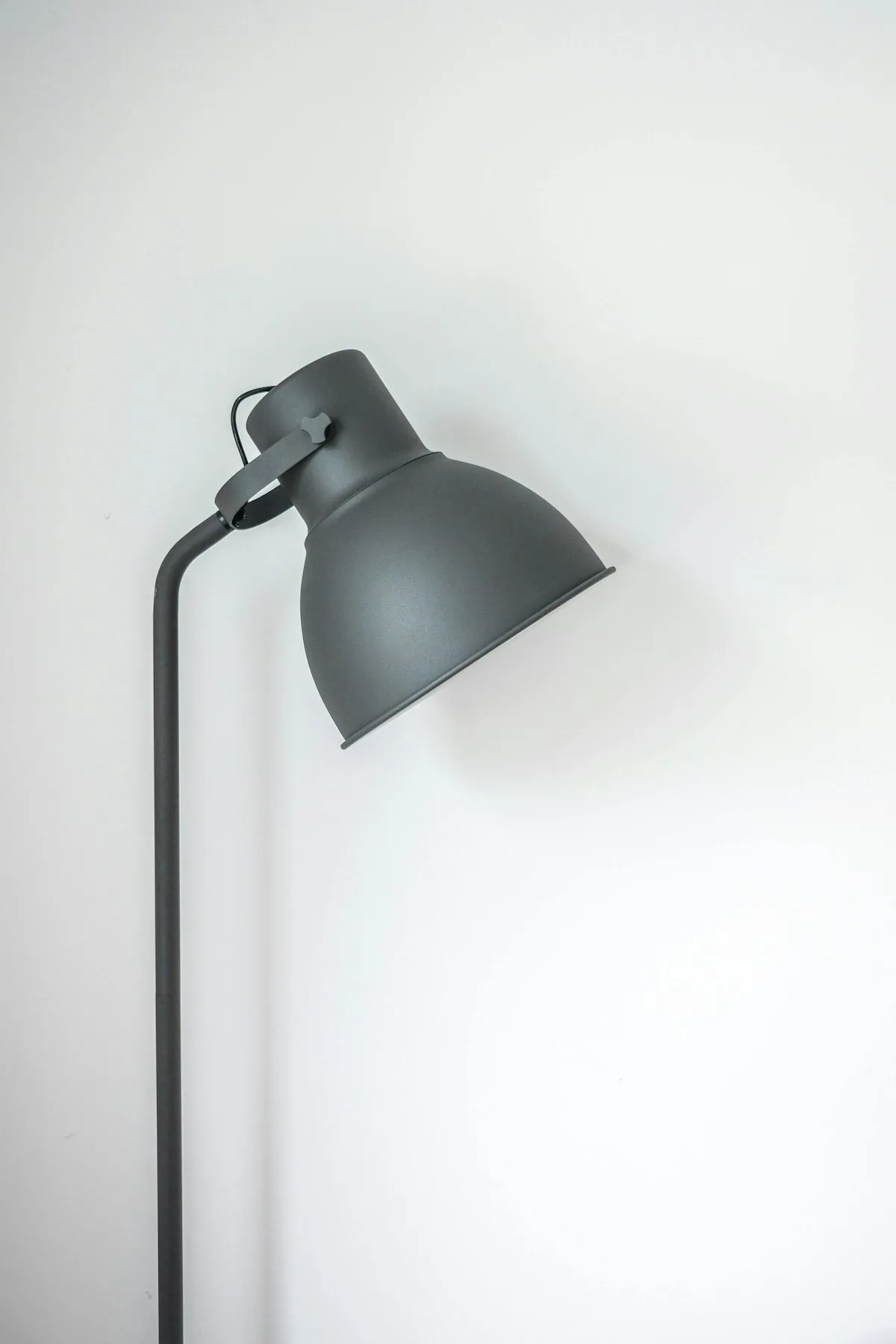 Minimalist cordless brass table lamp glowing with warm ambient light on bedside nightstand