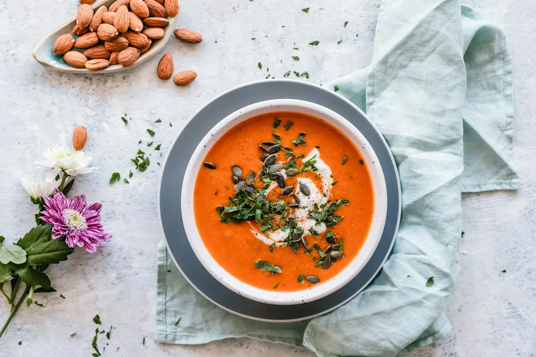 Warm bowl of smooth red lentil tomato soup garnished with parsley and cracked black pepper