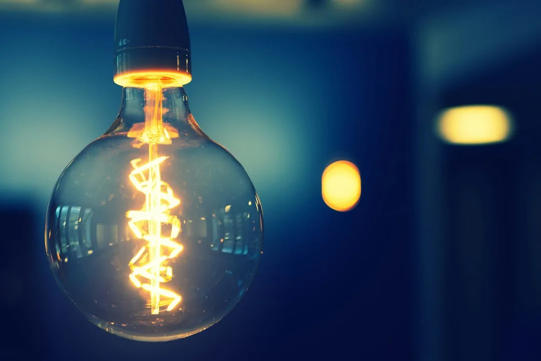 Close view of warm energy efficient LED filament light bulb glowing in desk lamp