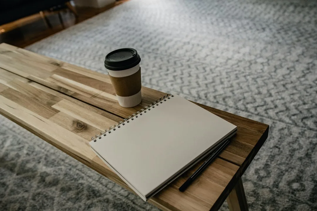 Open paper journal notebook with pencil tracking daily cash expenses on wooden table