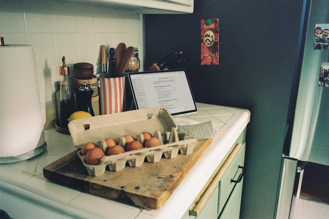 Handwritten grocery shopping list with pen resting on clean kitchen counter next to vegetables