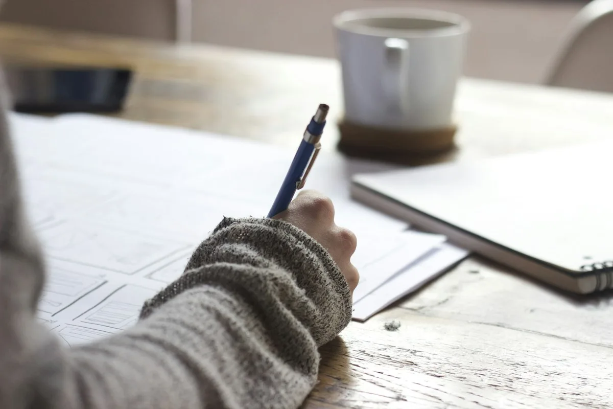 Person using yellow highlighter marking bill due dates on desk calendar planner