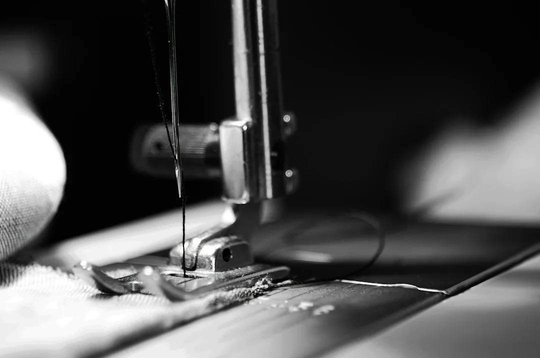 Close view of hand holding needle and thread repairing torn denim fabric patch