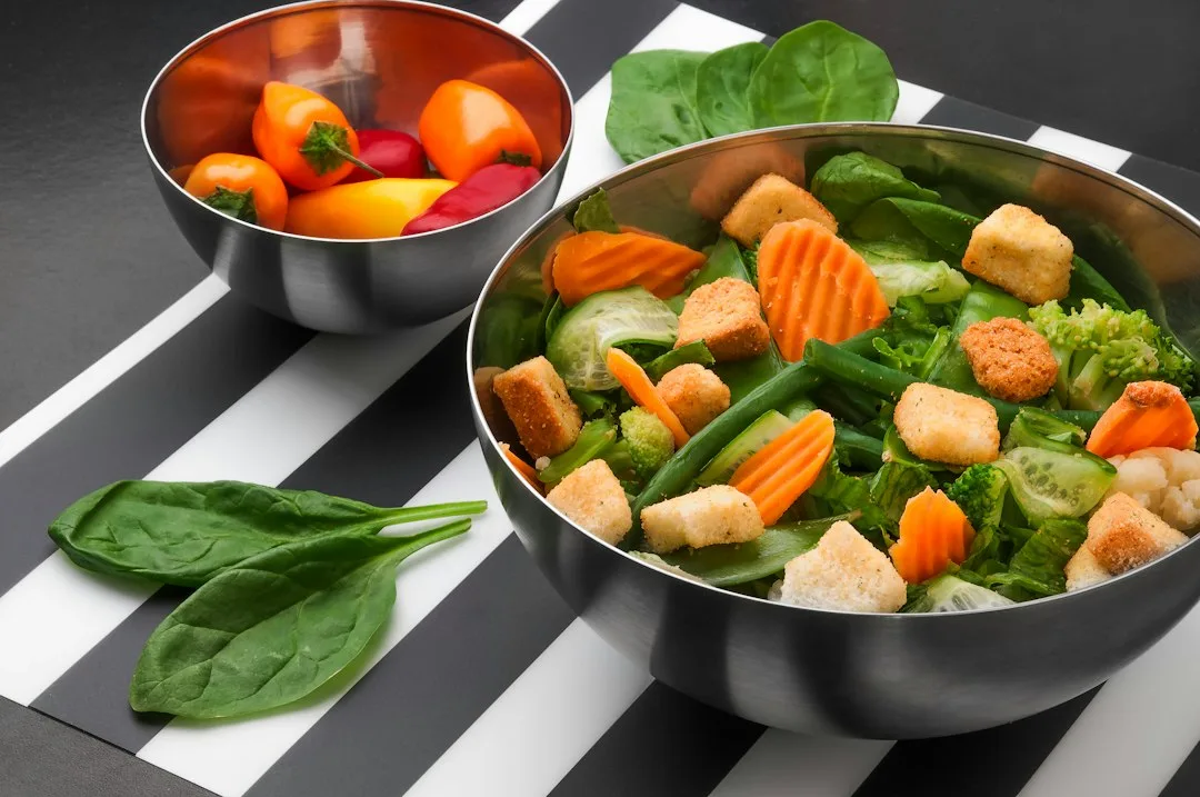 Open stainless steel lunch bento box filled with fresh colorful salad and grains