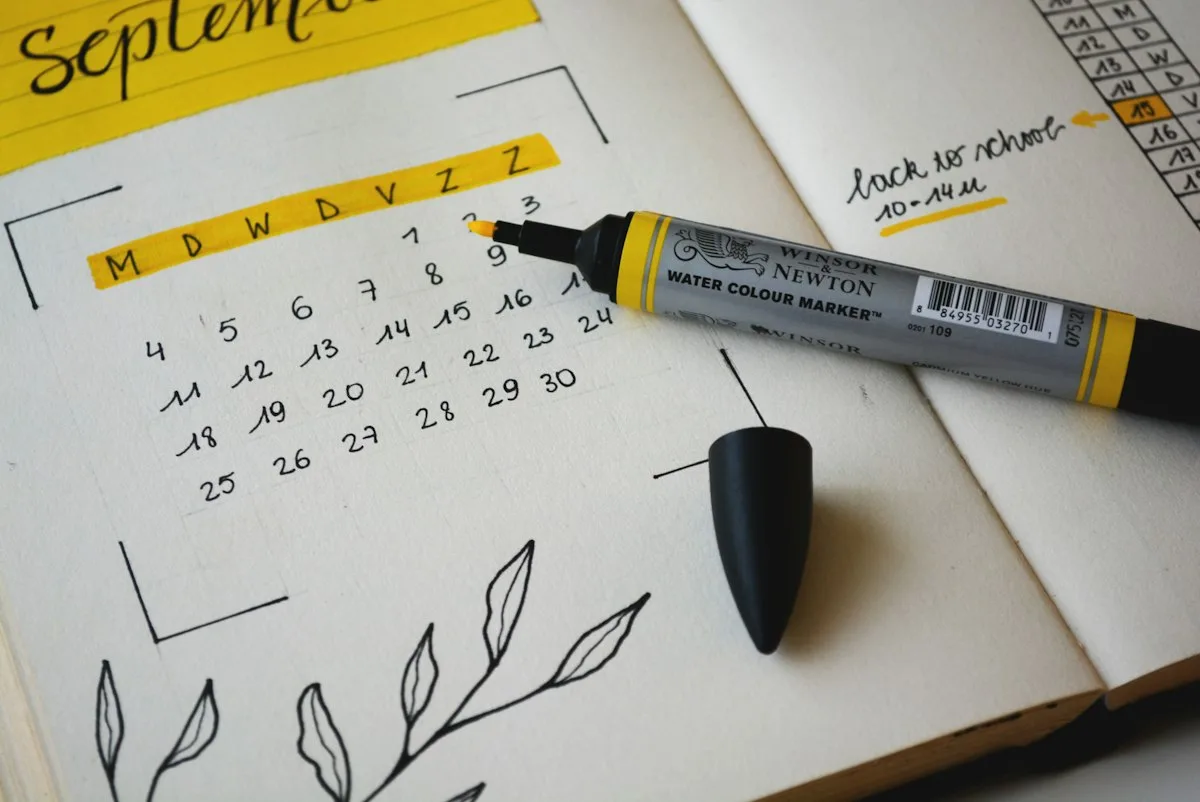 Open monthly planner notebook beside calculator on sunny desk ready for budget planning