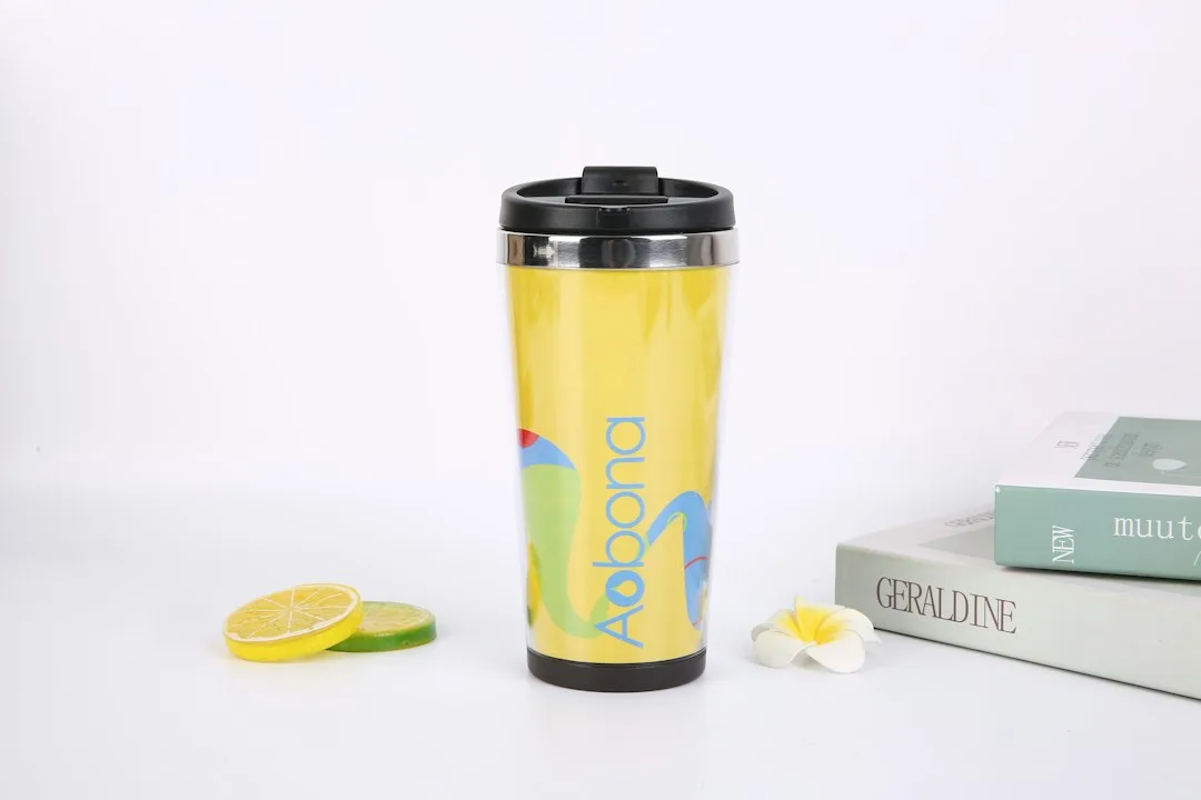Insulated stainless steel travel coffee tumbler mug sitting on clean wooden office desk