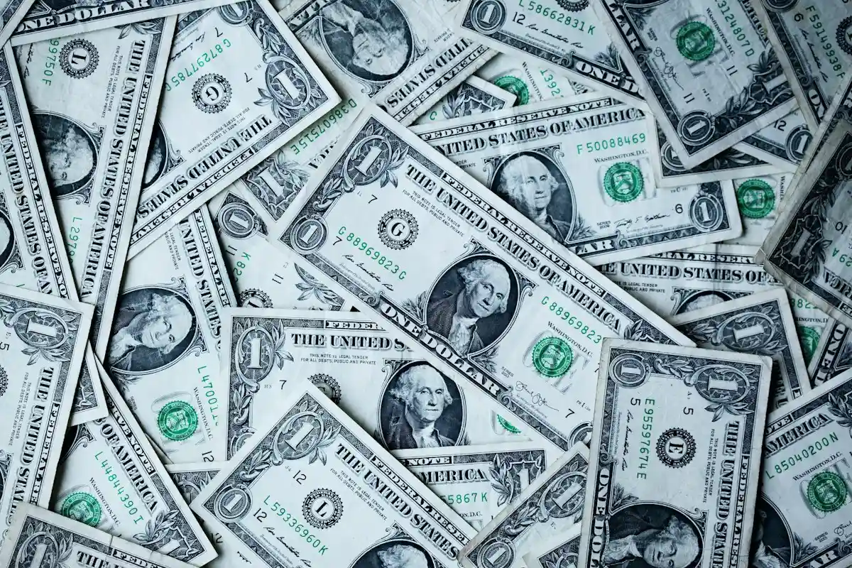 Hands counting and sorting paper dollar bills into neat piles by denomination on table